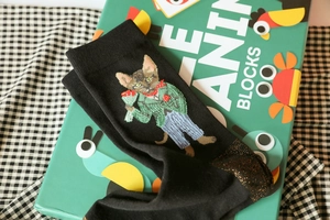 Close-up of cat embroidery and gold trim detail on black cotton ankle socks