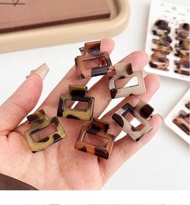 Close-up of six mini leopard print square hair claws held in hand for hair styling