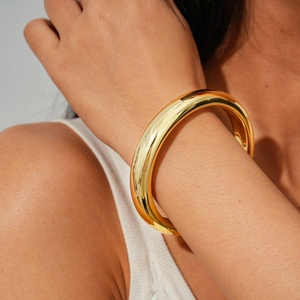 Macro detail of high-polish gold irregular geometric bangle on a model's wrist