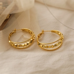 Detailed macro view of 18K gold-plated triple-layer geometric hoop earrings on soft fabric