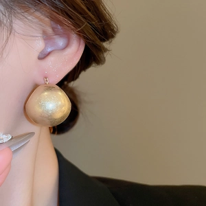 Close-up of matte gold U-shaped basket earrings on model with a vintage minimalist finish