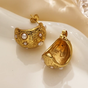 Detail of gold hammer-textured hoop earrings with embedded white pearls and studs