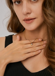 Close-up of minimalist gold beaded necklace with a single round zircon on a model