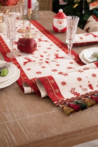 Close-up of red and beige Christmas table runner with reindeer pattern and tassel detail