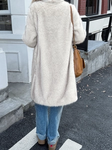 Manteau long élégant en fausse fourrure crème pour femme vue de dos en milieu urbain