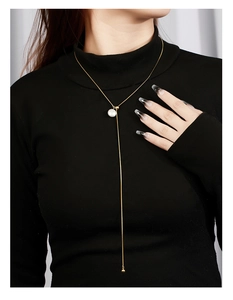 Macro detail of adjustable silver necklace with baroque pearl on a black sweater