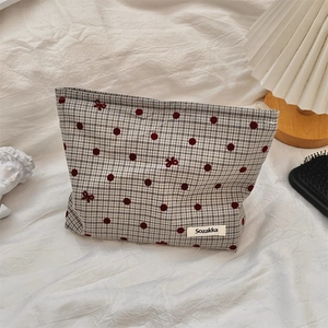 Close-up of a plaid makeup bag with red polka dots and a bow embroidery details
