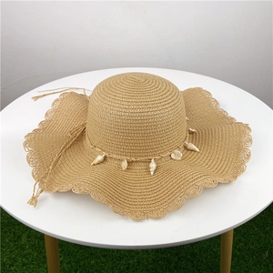 Detail of summer straw sun hat with shell decoration and stylish wavy brim texture