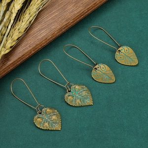 Gros plan de boucles d'oreilles ethniques en bronze avec patine verte sur fond texturé