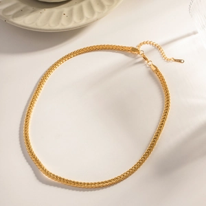 Detail of 18K gold plated braided chain necklace with lobster clasp on a ceramic plate
