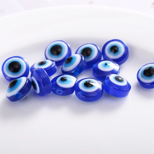 Macro shot of blue resin evil eye flat round beads on a white ceramic plate