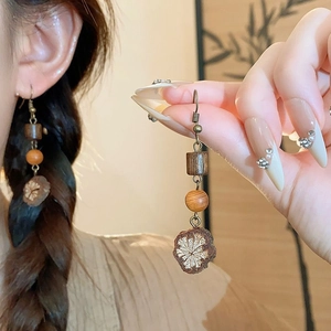 Détail de boucles d'oreilles vintage en bois à fleurs et pompons sur un mannequin