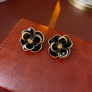 Macro shot of vintage black enamel camellia flower earrings with gold metallic edges