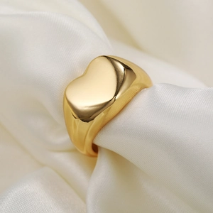 Gold heart signet ring elegantly displayed on premium white silk fabric for a luxury look