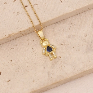 Detailed close-up of golden bear necklace with a blue heart zircon on beige stones