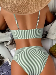 Rear view of green and white striped high-waisted bikini set with ruffles and straw hat