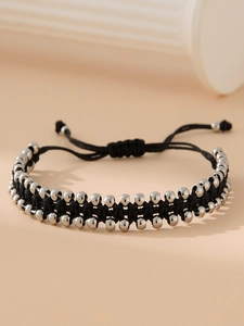 Détail d'un bracelet tissé main avec corde noire, perles en acier et nœud ajustable