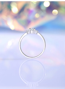 Macro shot of silver three-stone ring with round moissanite on a bokeh background