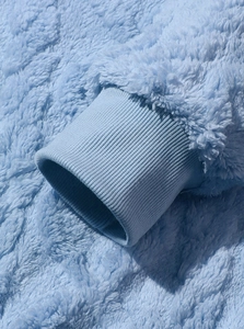 Dettaglio del tessuto pile azzurro e del polsino a coste su una felpa con cappuccio