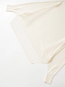 Detailed close-up of ribbed cuffs and fine knit texture on a cream-colored sweater