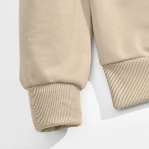 Close-up of ribbed cuffs and hem on beige corduroy patchwork crewneck sweatshirt