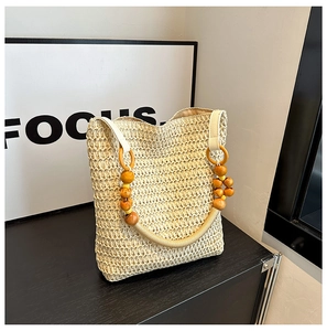 Detailed view of beige straw woven bag with wooden bead rope handle for beach vacation
