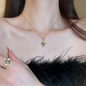 Close-up detail of a gold-plated flower clover necklace and ring set worn by a model