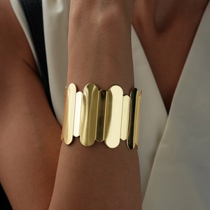 Polished gold wave-edge cuff bracelet with wide geometric metal strips shown on model