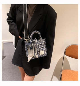 Detail of blue checker canvas tote with top handles and Paris ribbon on a black blazer