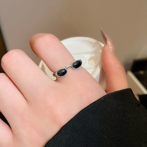 Macro shot of silver y2k sunglasses ring with black enamel details on model finger