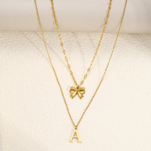 Close-up of gold double-layer necklace with bow pendant and initial A charm