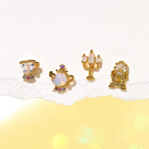 Detail of gold-plated stud earring set featuring teapot, teacup, clock and candle shapes