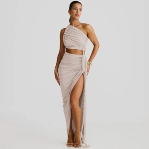 Detail of beige two-piece dress featuring one-shoulder crop top and pleated side slit skirt