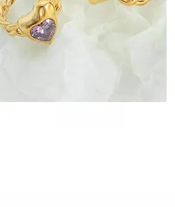 Macro detail of a twisted golden chain ring featuring a heart-shaped purple gemstone