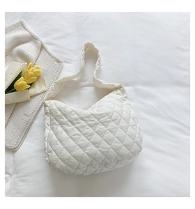Close-up of white quilted nylon bag texture with tulip decor on soft bedding