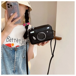Detail of camera-shaped black crossbody bag with metallic accents and retro style