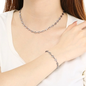 Détail de l'ensemble collier et bracelet à maillons grain de café argentés sur un mannequin