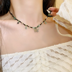 Detail of beaded necklace with green stone beads and a gold butterfly pendant
