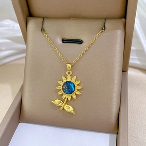 Détail du pendentif tournesol doré orné d'un cristal bleu sur sa chaîne en maille