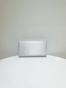 Elegant silver satin evening clutch with horizontal pleated trim on a white display stand