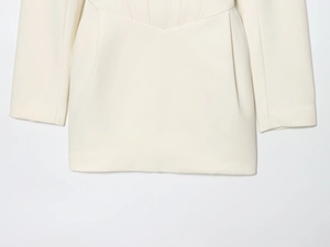 Détail de la taille ajustée et de l'ourlet structuré sur robe blazer blanc crème