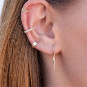 Detailed view of gold-plated spiked earrings and cubic zirconia ear cuffs on model