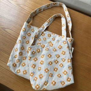 Detail of small and large canvas tote bags with delicate yellow flower embroidery