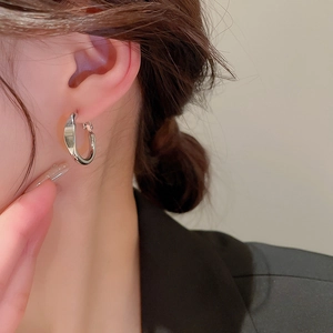 Minimalist silver geometric twisted hoop earrings for women shown on model ear
