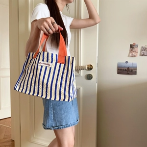 Close-up of blue striped canvas tote bag with textured fabric and orange handles