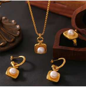 Detail view of vintage gold textured jewelry set with white pearls in a wooden gift box