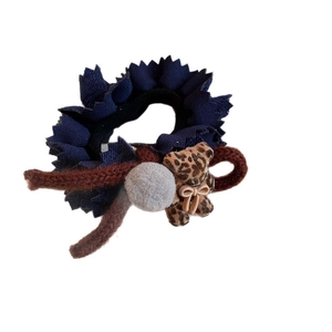Blue pleated fabric hair tie featuring a leopard print bear charm and a grey pompom