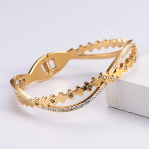 Macro shot of gold-plated hollow bracelet with pavé-set rhinestones on a white cube