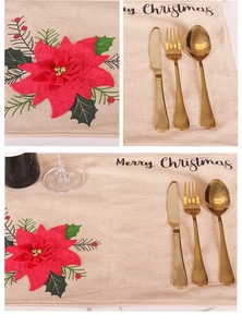 Detailed macro view of beige faux linen Christmas placemat with poinsettia print and cutlery