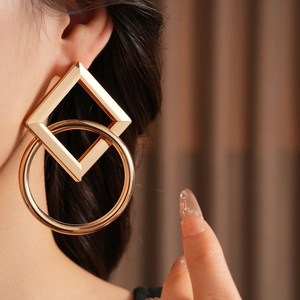 Gros plan détaillé des boucles d'oreilles géométriques carrées et rondes dorées sur modèle